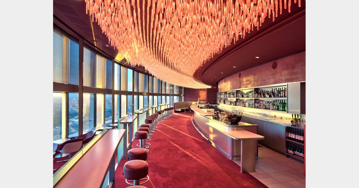 En arrivant au Bar "La Vue", vous pouvez expérimenter deux sensations spatiales opposées et distinctes, qui ne dépendent ni de la décoration ni du mobilier. Tout d'abord, vous pouvez ressentir une sensation de compression en vous déplaçant dans le noyau central du bâtiment, puis, en vous approchant des baies vitrées, vous pouvez éprouver un sentiment d'ouverture et d'expansion. Le design cherche à créer une interface architecturale qui transforme cette opposition en une expérience sensorielle enrichissante. Le sol et le plafond sont conçus pour faciliter l'expression et la perception de ces conditions. En effet, trois marches en contrebas du niveau d'accès principal, associées à trois plans de plafond qui se dilatent, augmentent l'angle de perception et créent une sorte d'image de kaléidoscope.