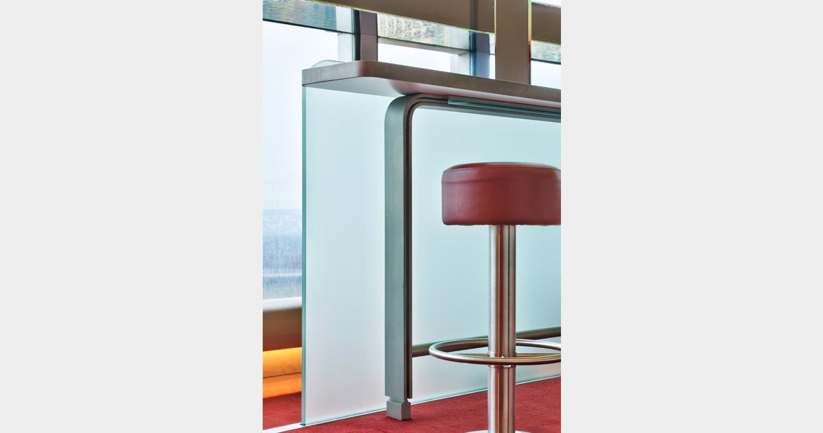 En arrivant au Bar "La Vue", vous pouvez expérimenter deux sensations spatiales opposées et distinctes, qui ne dépendent ni de la décoration ni du mobilier. Tout d'abord, vous pouvez ressentir une sensation de compression en vous déplaçant dans le noyau central du bâtiment, puis, en vous approchant des baies vitrées, vous pouvez éprouver un sentiment d'ouverture et d'expansion. Le design cherche à créer une interface architecturale qui transforme cette opposition en une expérience sensorielle enrichissante. Le sol et le plafond sont conçus pour faciliter l'expression et la perception de ces conditions. En effet, trois marches en contrebas du niveau d'accès principal, associées à trois plans de plafond qui se dilatent, augmentent l'angle de perception et créent une sorte d'image de kaléidoscope.