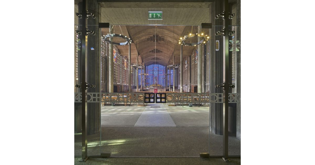 Création d’un sas vitré translucide permettant une vision privilégiée permanente depuis la rue principale sur les volumes et les vitraux de ce lieu d’exception sans que les fidèles ou les touristes ne soient affectés par les intempéries et les bruits émanant de la rue.