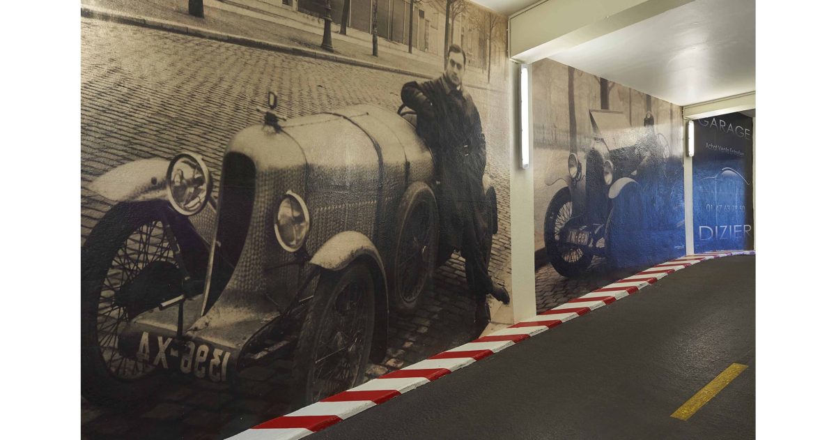 Aménagement d'un accès de garage. Le garage Robert Dizier est reconnu depuis trois générations par les plus grands amateurs de voitures d'exception (Porsche, Lotus, Jaguar, Bentley, ...). Pour référer à la pérennité de cette institution, des impressions numériques HD positionnées sur les murs de la rampe d'accès représentent le fondateur posant devant une Lorraine Dietrich en 1925 et devant une Amilcar en 1938.